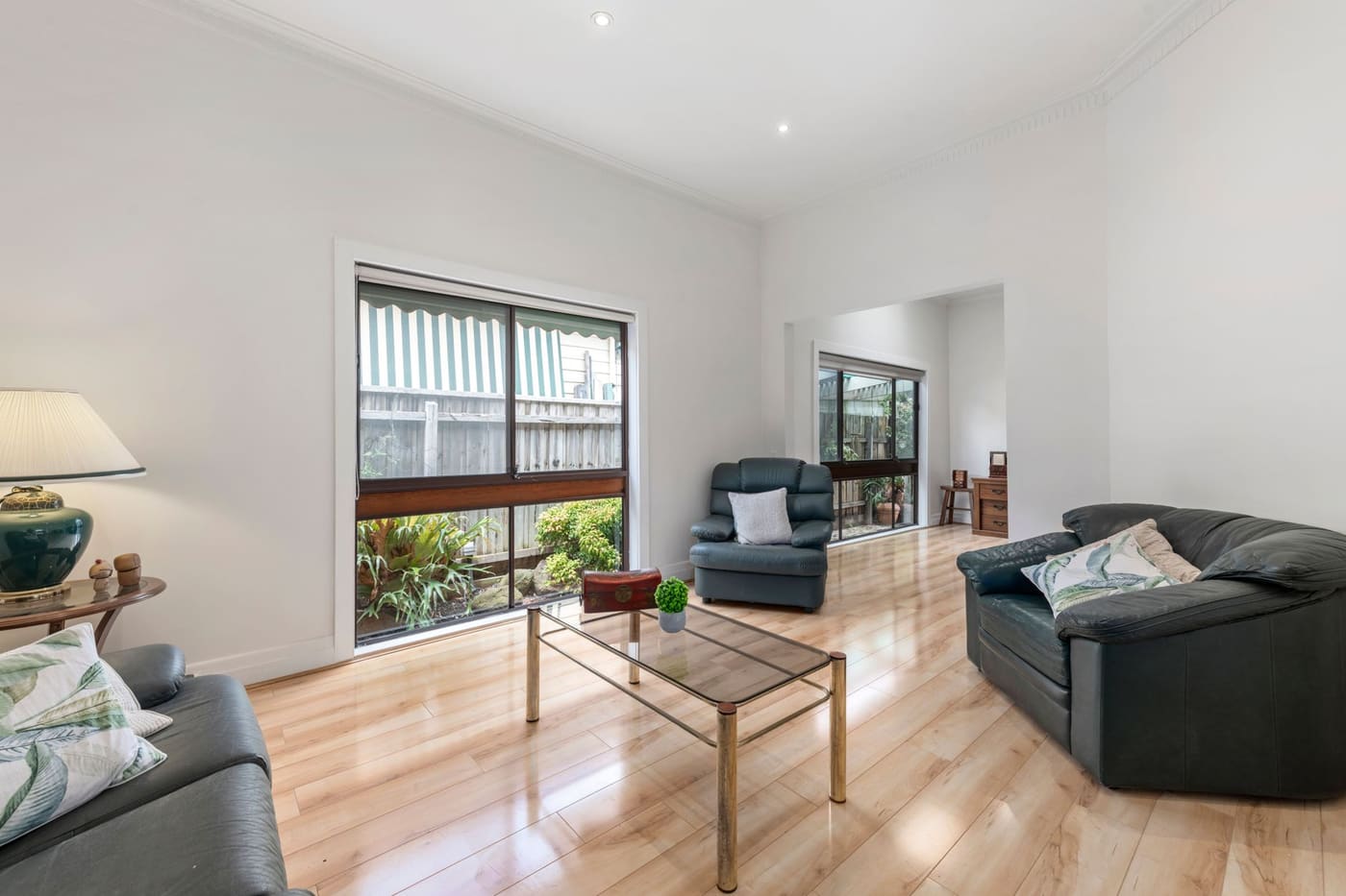 Bright living room with a dark sofa, an armchair and a glass coffee table on a wood floor
