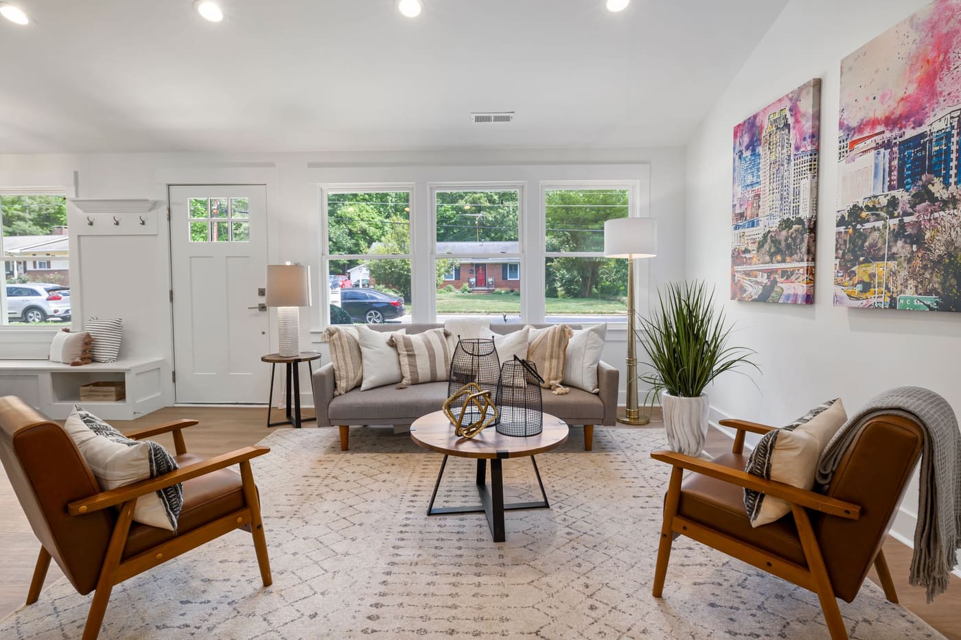 Sofa and two wooden armchairs around a round coffee table on a patterned rug