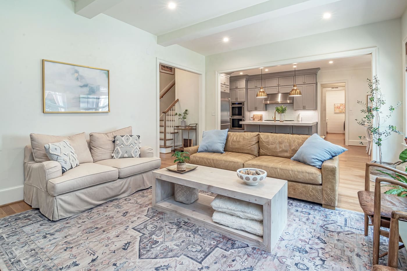 Living room with two sofas on a large patterned rug and an open kitchen beyond