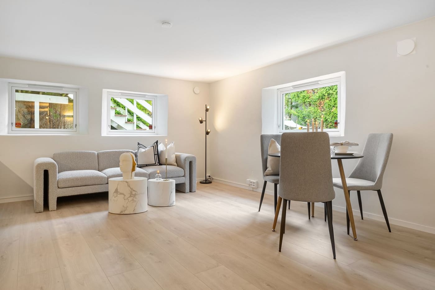 Open-plan room with a gray sofa in the living area and a dining table beyond