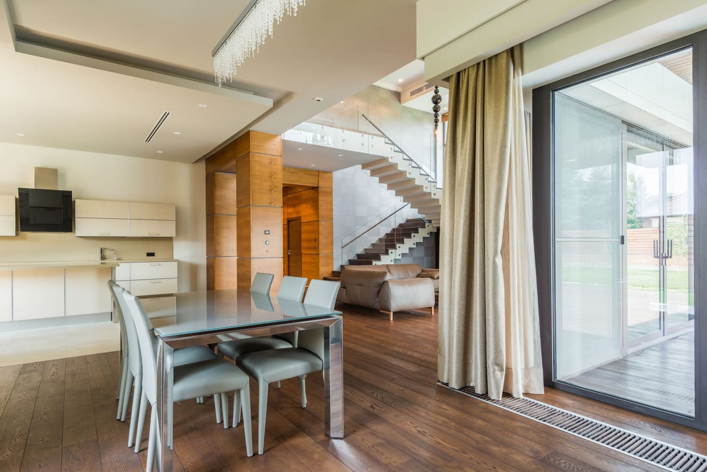 Open-plan living and dining area with a glass wall and long curtains