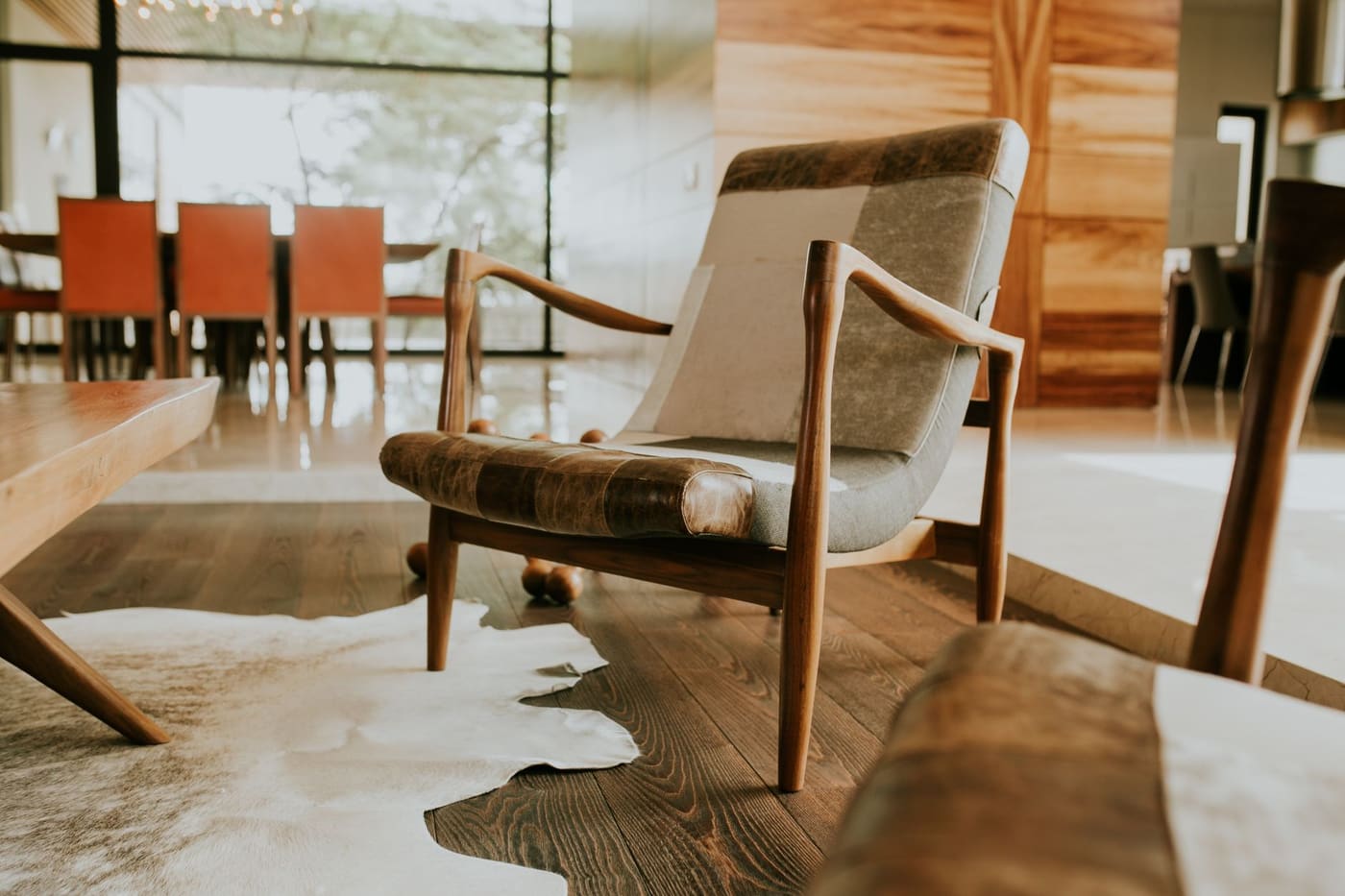 Wooden armchair with a patterned seat on a cowhide rug over a wood floor
